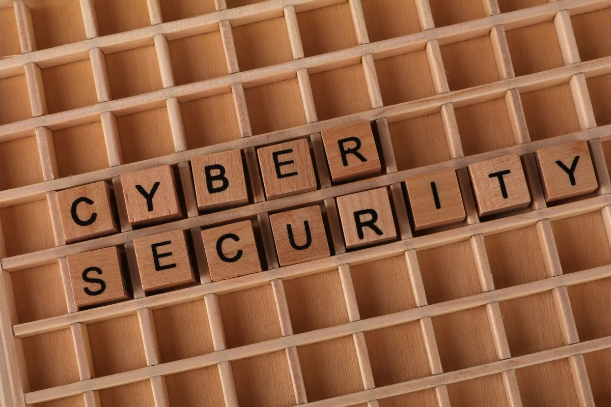 Ahşap bloklar üzerinde yazan 'Cyber Security' (Siber Güvenlik) ifadesi, kurumsal veri güvenliğini temsil ediyor.